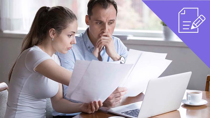 casal jovem a verificar faturas com computador portátil