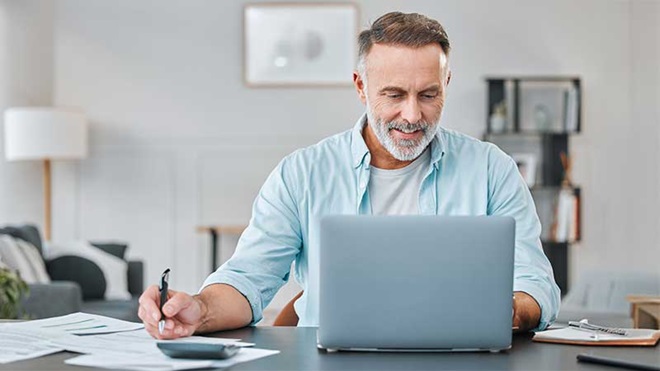 homem com calculadora e moedas em cima da mesa
