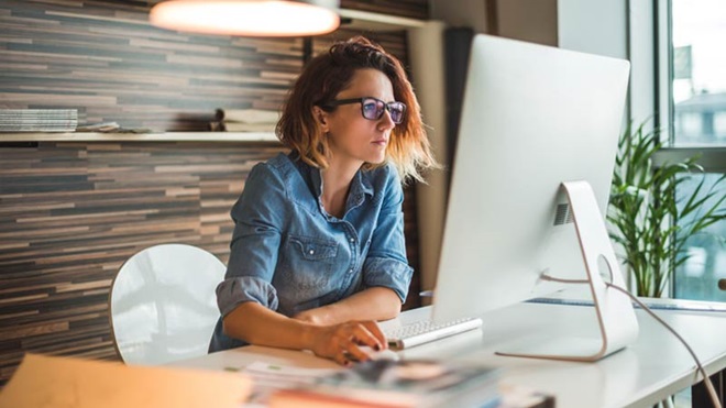 Jovem mulher ao computador a preencher os novos recibos verdes