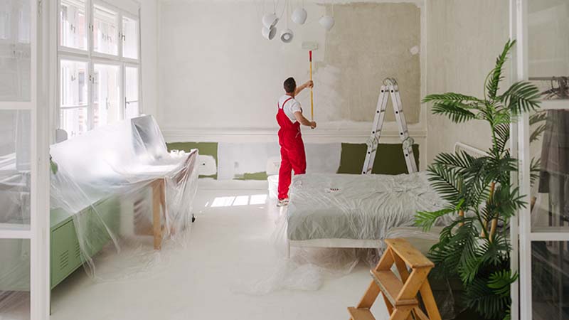 Trabalhador com fato macaco vermelho a remodelar uma sala