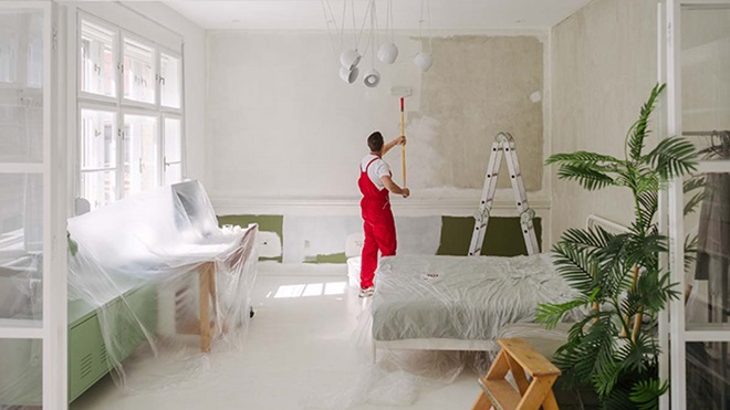 Trabalhador com fato macaco vermelho a remodelar uma sala