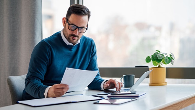 Homem a analisar documentos à secretária