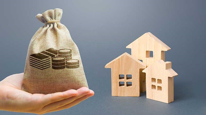 Mão com saco de dinheiro e casinhas de madeira