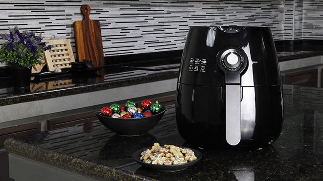 Airfryer em cima da bancada da cozinha, um prato com bolachas de Natal e uma taça com bolas de Natal
