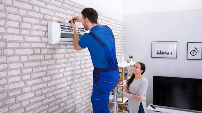 técnico a instalar unidade interior de aparelho de ar condicionado na sala de uma cliente