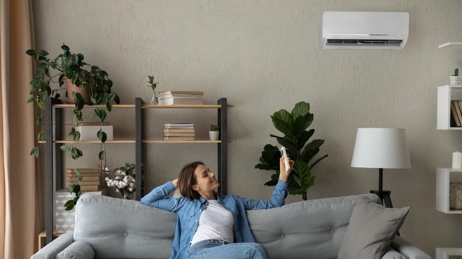 mulher sentada num sofá a colocar o ar condicionado a trabalhar