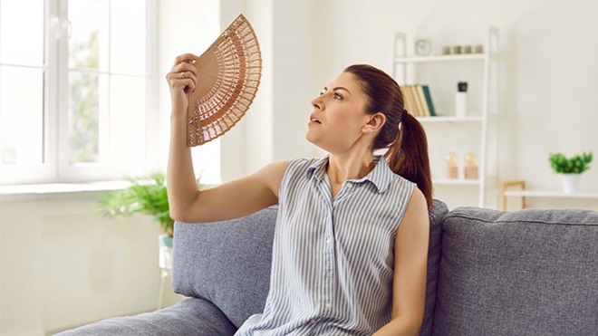 Mulher a abanar-se com um leque na sala durante uma vaga de calor