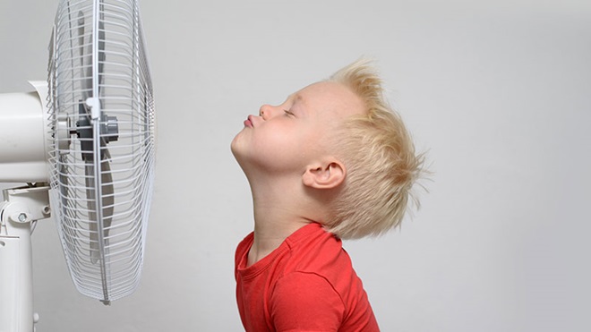 criança à frente de uma ventoinha