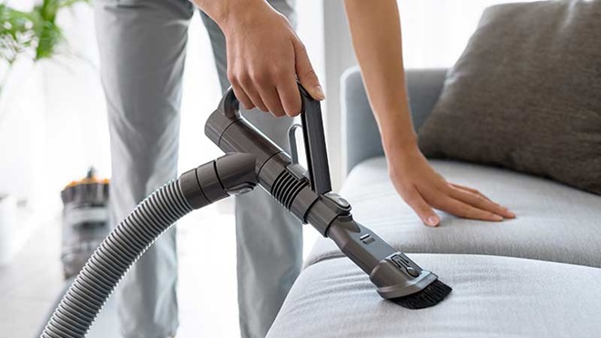 mulher a aspirar o sofá com acessório