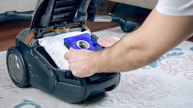 Homem a mudar saco do aspirador