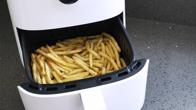 Fritadeira branca a ar com batatas fritas aos palitos na gaveta