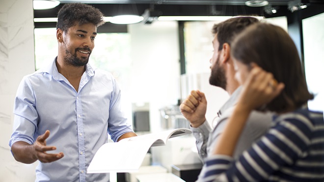 vendedor com casal numa loja a apresentar documento