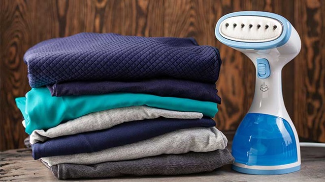 ferro de engomar portátil junto a pilha de roupa
