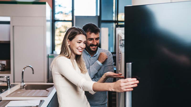 Casal na cozinha a abrir a porta do frigorífico