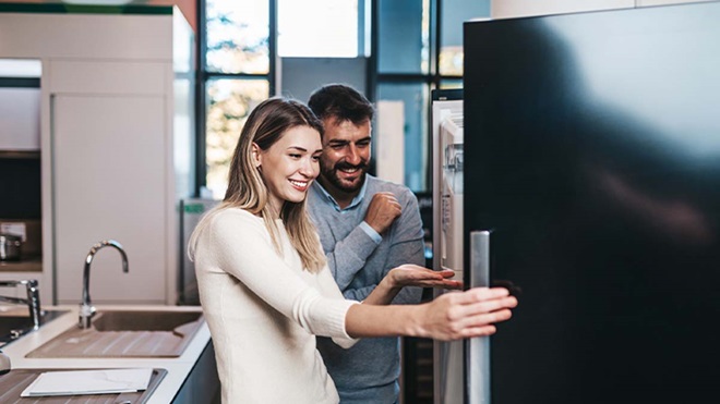 Casal na cozinha a abrir a porta do frigorífico