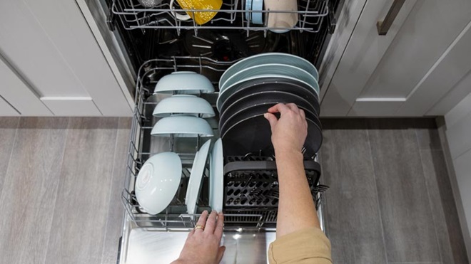 pessoa a colocar loiça na máquina de lavar loiça