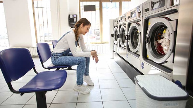 Rapariga à espera na lavandaria self-service