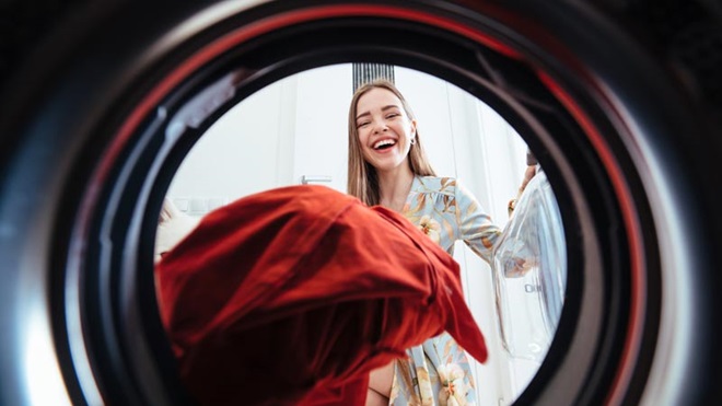 mulher a colocar roupa numa máquina de secar roupa