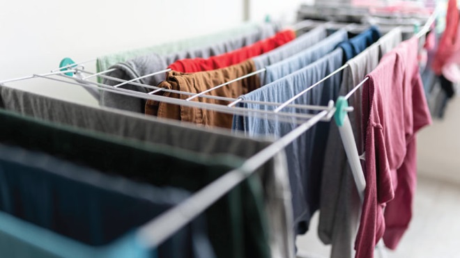 Estendal metálico de pé carregado de roupa a secar no interior de uma casa 