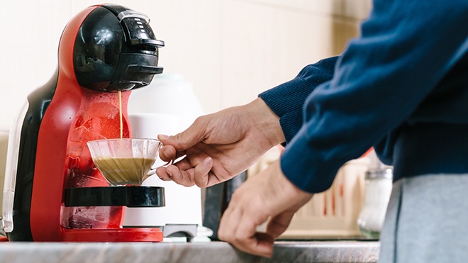 homem em casa a tirar café da máquina