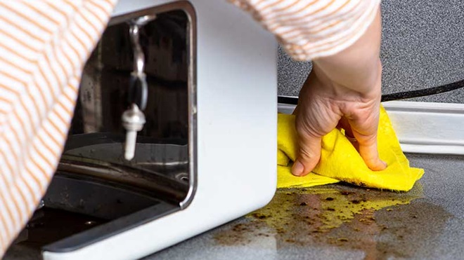 pessoa a limpar água por baixo de máquina de café