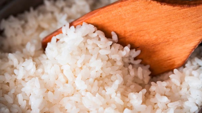 Grande plano de arroz a ser confecionado, mexido com uma colher de pau