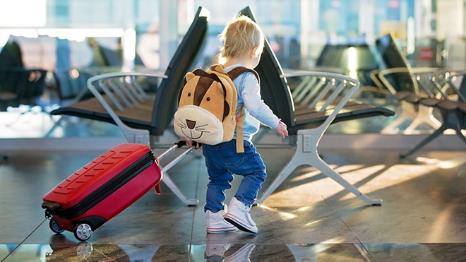 criança a empurrar trólei de viagem no aeroporto