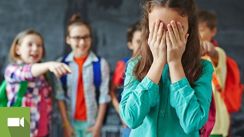 rapariga com as mãos na cara a ser vítima de bullying
