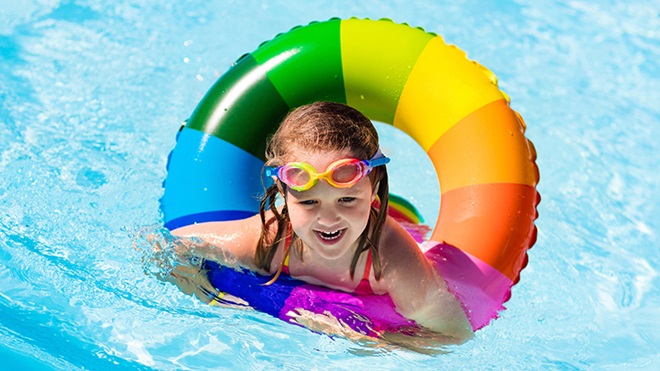 criança na piscina a nadar com a ajuda de uma bóia