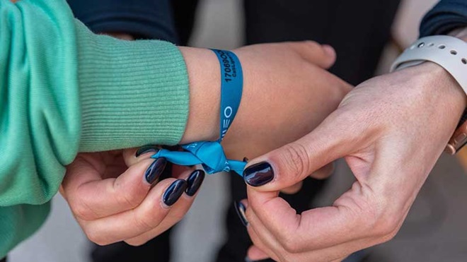 Mulher a colocar pulseira Estou Aqui em criança