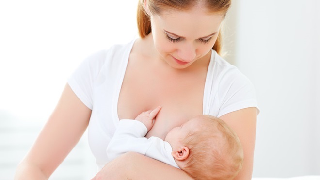 Mãe a amamentar um bebé, vestidos de branco