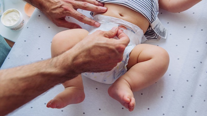 Mãos a mudar uma fralda num bebé