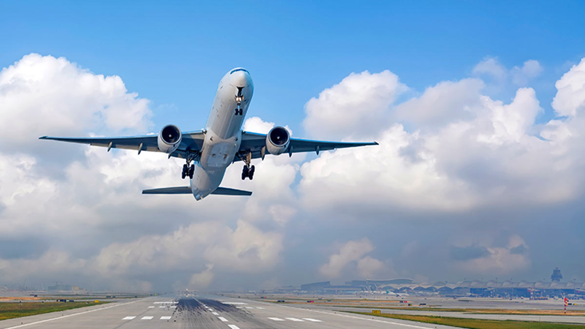 Avião a levantar voo num aeroporto, céu azul com nuvens