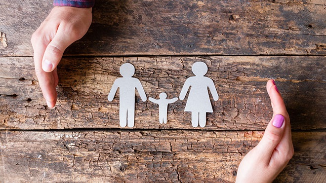 família em papel e duas mãos