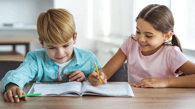 Duas crianças com um livro escolar