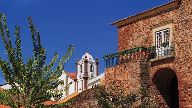 Silves e muralhas do castelo de vermelho-escuro. Tom deve-se a rocha do local, grés de Silves.