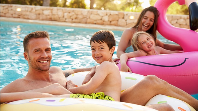 Família de quatro a brincar na piscinas com boias