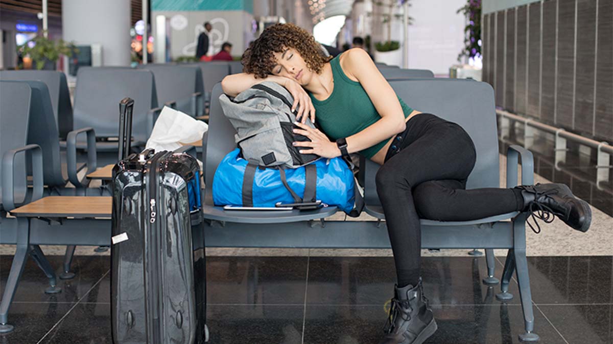 Mulher a dormir encostada às malas num aeroporto