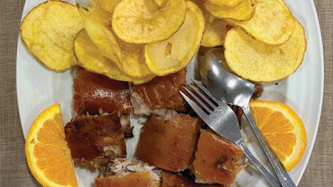 Travessa de leitão assado com pele estaladiça, rodelas de laranja e batatas fritas