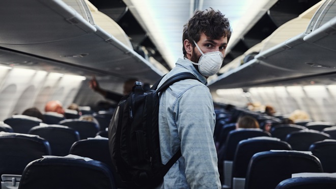 Pessoa dentro de avião com máscara
