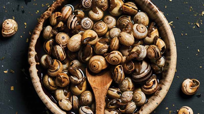 Taça de caracóis com colher de pau na mesa 