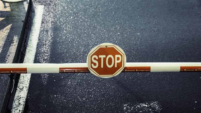 sinal de stop sobre cancela a proibir passagem numa estrada