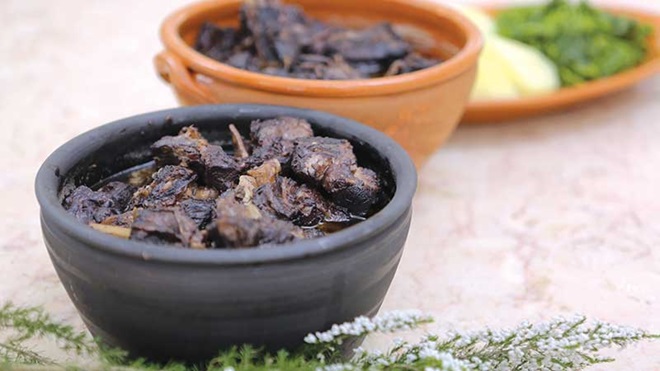 Duas caçoilas de chanfana e travessa de acompanhamento em cima de uma mesa