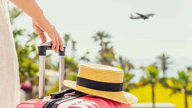Mulher com mala de viagem e chapéu de palha 