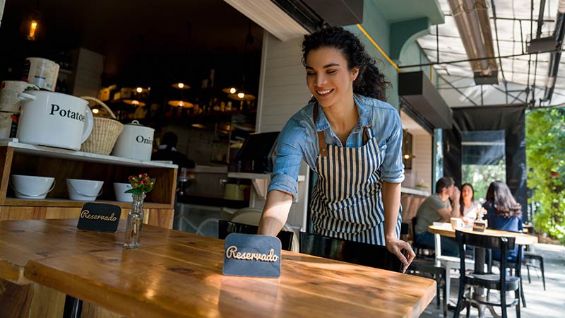 Empregada de restaurante a colocar placa de reservado na mesa