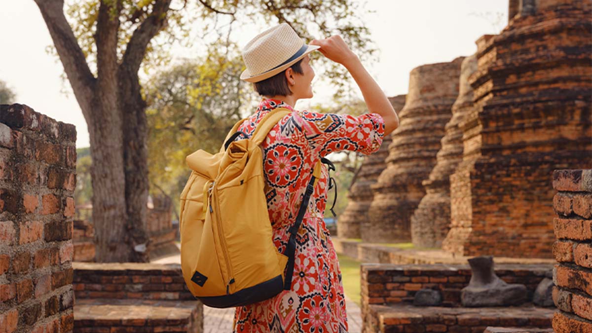 Turista em destino exótico com panamá e mochila amarela às costas