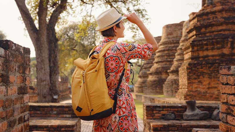 Turista em destino exótico com panamá e mochila amarela às costas
