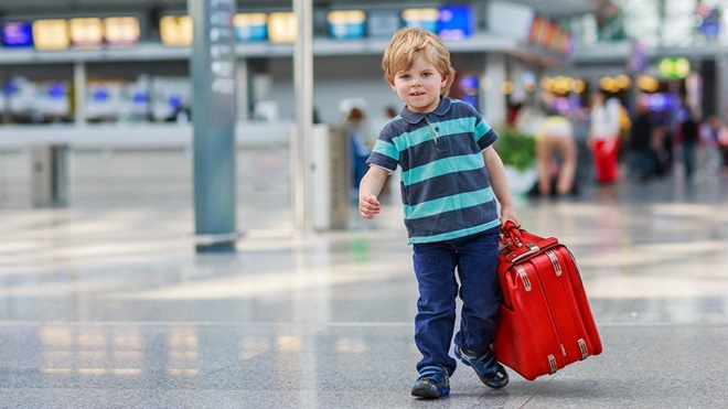 Criança no aeroporto a partir em viagem com uma mala 