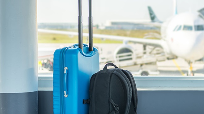 Malas de viagem em sala de espera do aeroporto com avião ao fundo