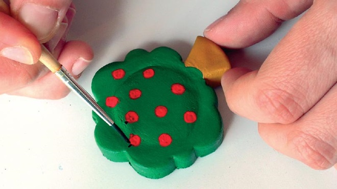 pessoa a pintar um íman para recados